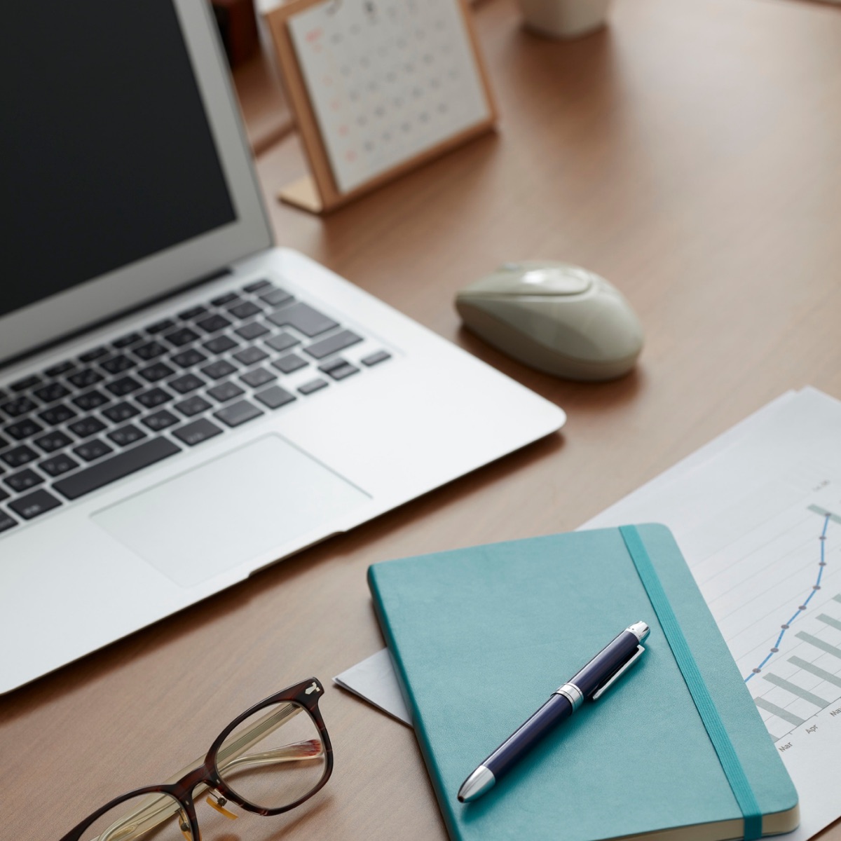 Bureau avec ordinateur portable, agenda et souris, ambiance de travail organisée