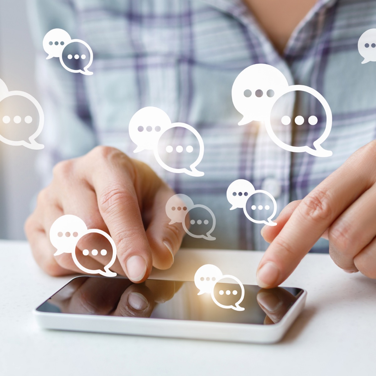 Mains tenant un téléphone avec des bulles de messages, symbole de communication et de réseaux
