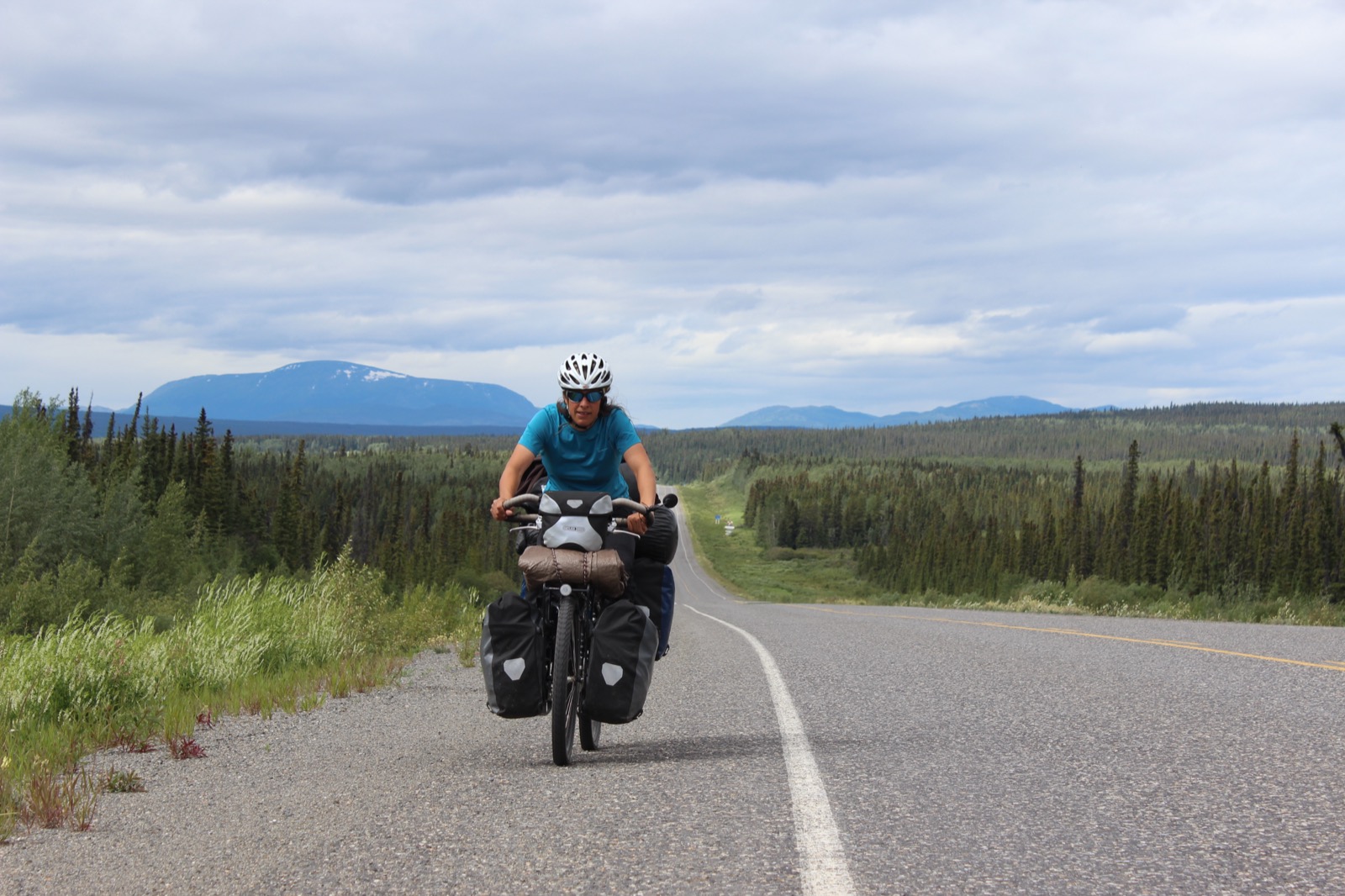 Marie-Ève à vélo en voyage, casque et sacoches, symbole de résilience et d'aventure